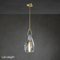 A gold-colored metal pendant light with a clear glass shade, suspended by a chain, against a dark background.