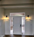White door with glass panels flanked by wall lights on a neutral wall.