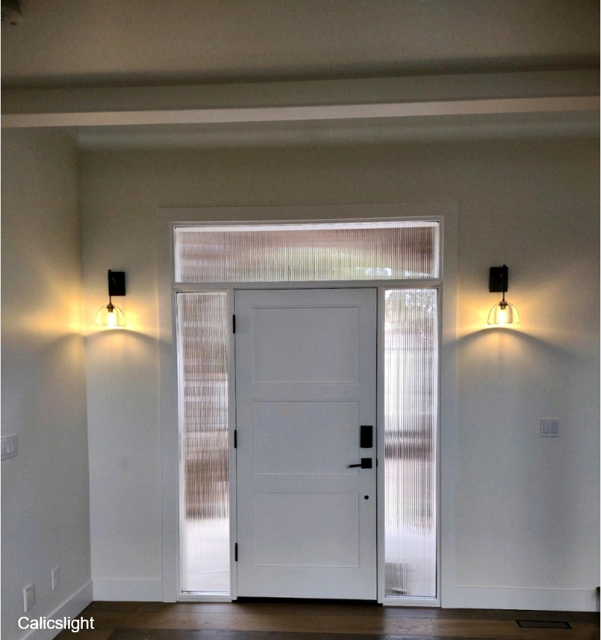 White door with glass panels flanked by wall lights on a neutral wall.