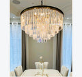 Chandelier hanging above a dining table in a room with curtains and chairs.