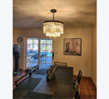 Dining room with a chandelier, table, chairs, and a view of the outdoors through a glass door.