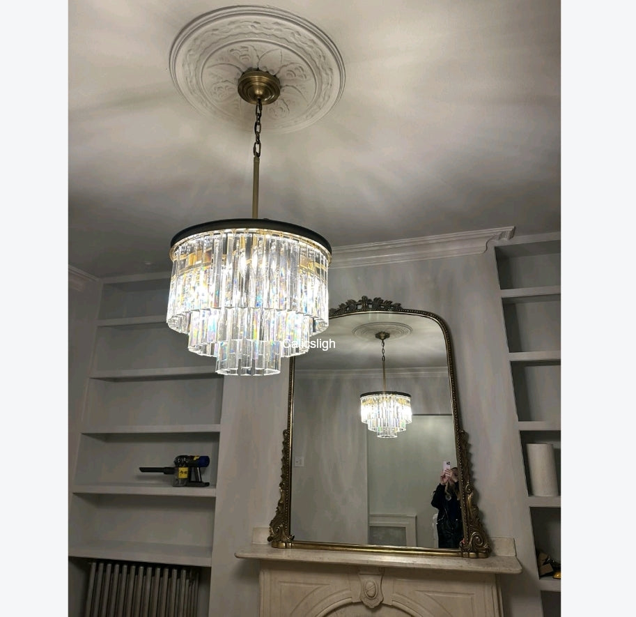 Chandelier hanging above a mirror in a room with shelves and decorative elements.