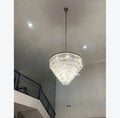 Crystal chandelier hanging from a ceiling in a room with a staircase.