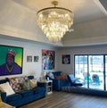 Living room with a chandelier, blue sofa, and colorful artwork on the walls.